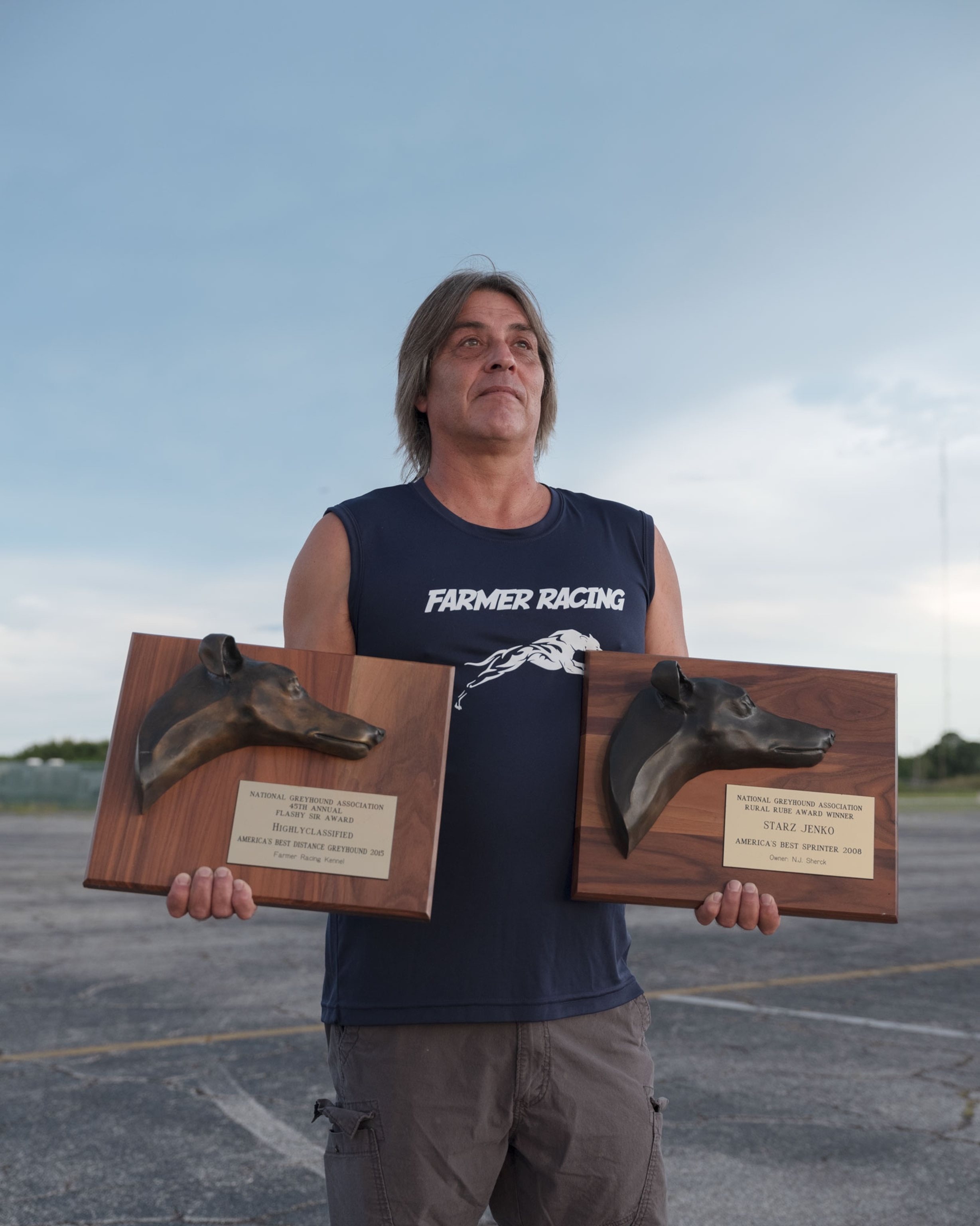 a man holding two greyhound medals in his hands