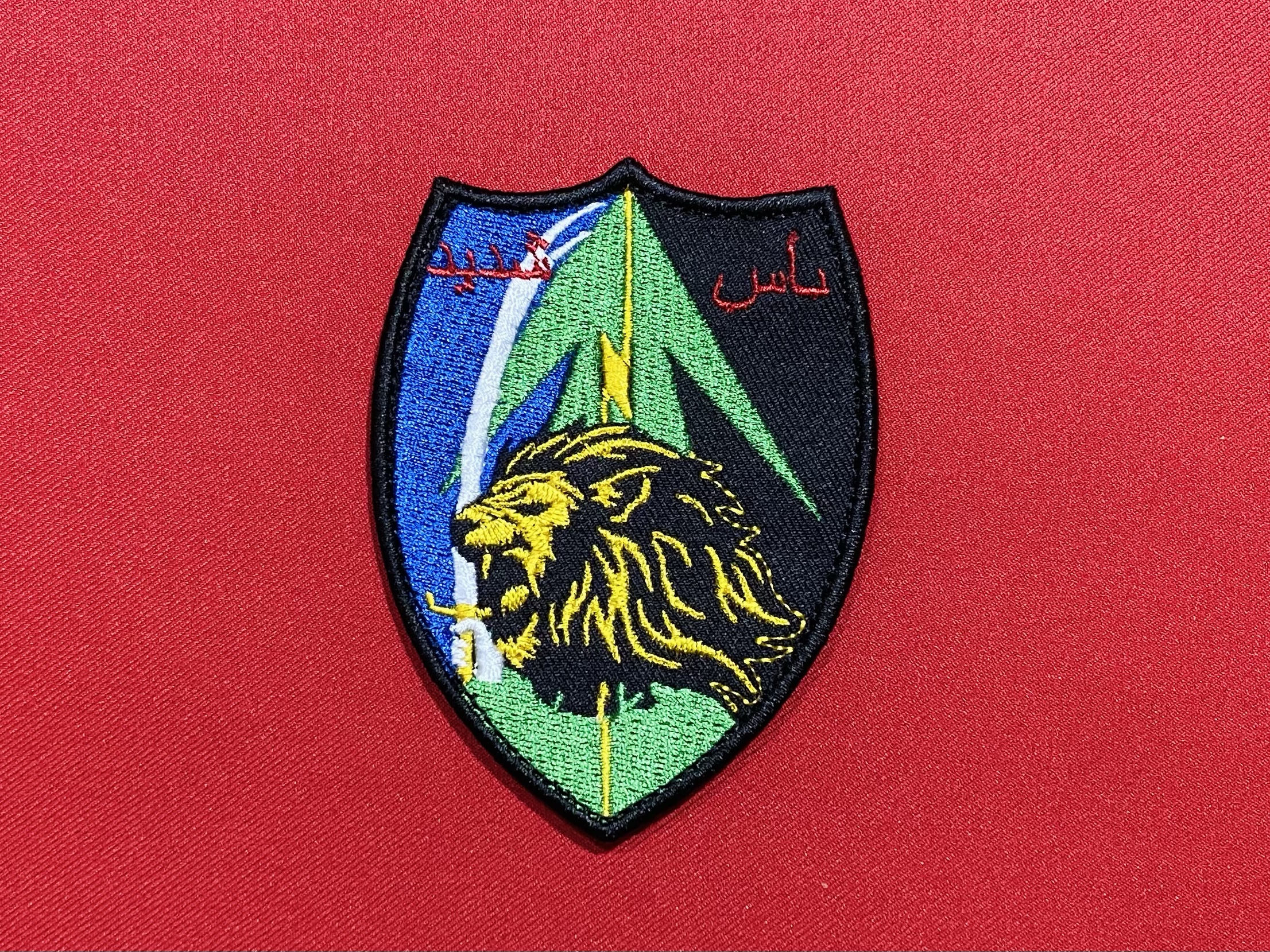 A detailed embroidered patch of Hezbollah's elite Radwan Force, featuring bold Arabic script and the distinctive emblem symbolizing the unit's strength and commitment. The patch showcases the unit's renowned insignia used by members of Hezbollah's special operations force, reflecting their elite status and rigorous training