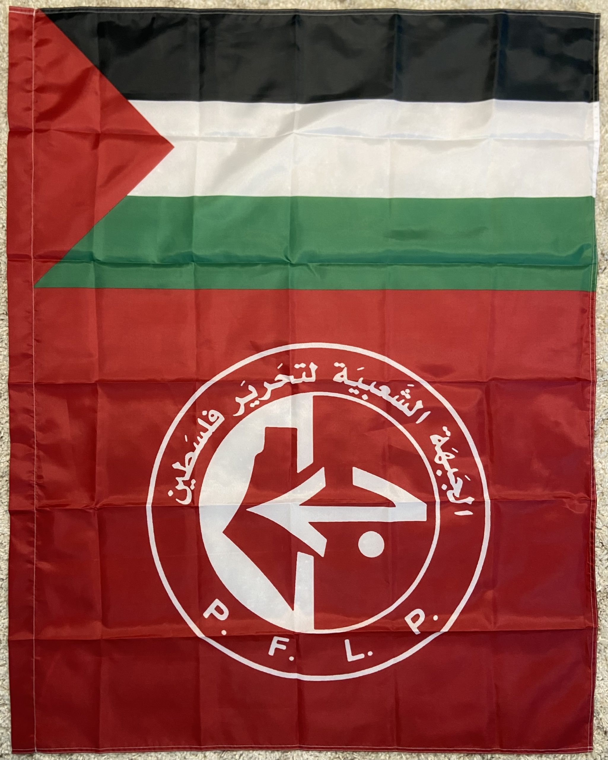 150x90 cm PFLP flag featuring the colors red, white, green, and black with the emblem of the Popular Front for the Liberation of Palestine (PFLP). The emblem includes Arabic text and a stylized arrow design, symbolizing Palestinian resistance and solidarity. Perfect for indoor and outdoor display, rallies, and personal collections