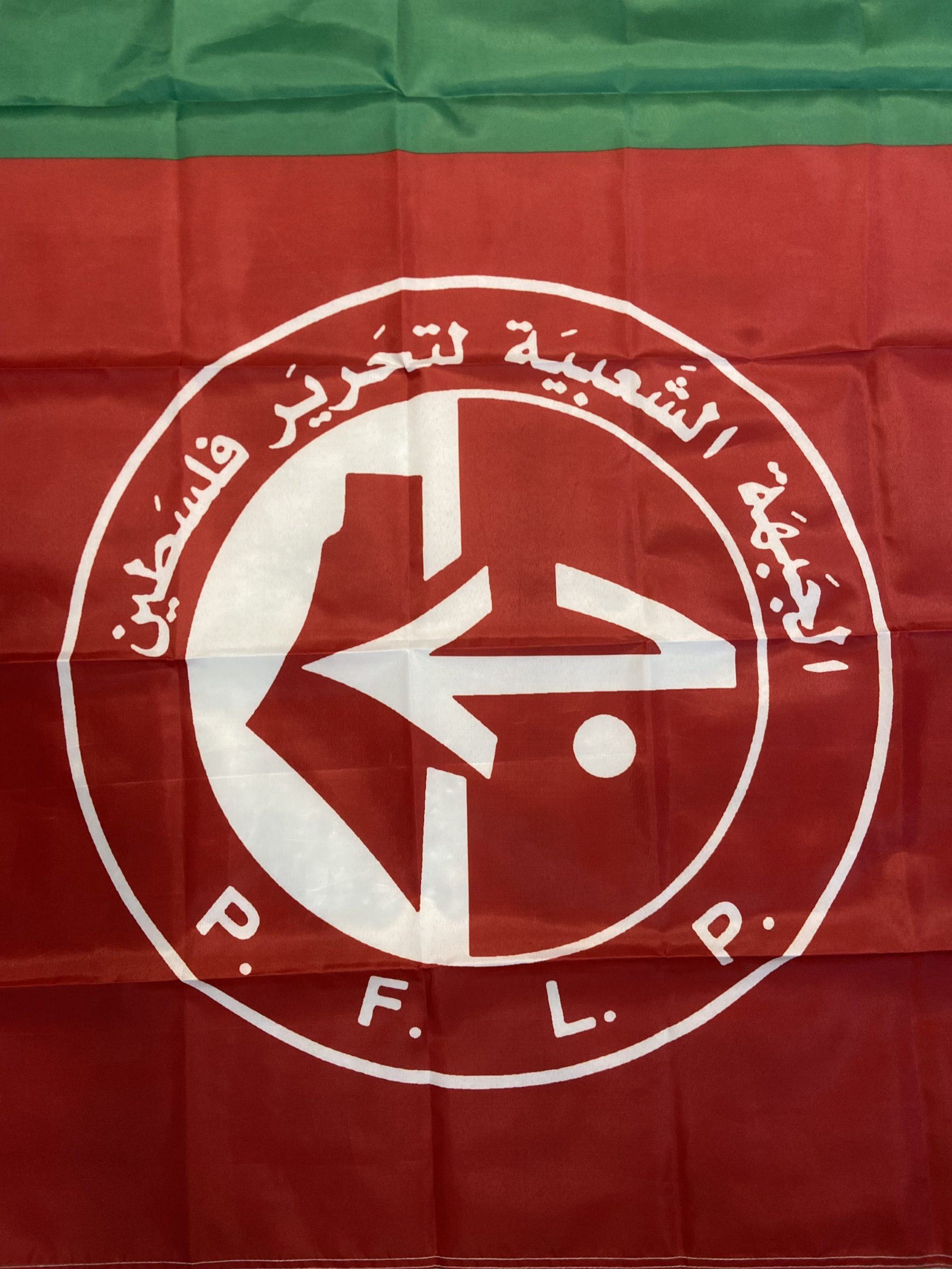 150x90 cm PFLP flag featuring the colors red, white, green, and black with the emblem of the Popular Front for the Liberation of Palestine (PFLP). The emblem includes Arabic text and a stylized arrow design, symbolizing Palestinian resistance and solidarity. Perfect for indoor and outdoor display, rallies, and personal collections