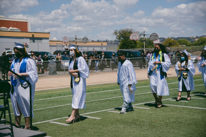 Los graduados hacen fila para recibir sus diplomas durante una ceremonia de graduación en Madison Park Academy en Oakland el 21 de mayo de 2021. Foto de Marissa Leshnov para CalMatters
