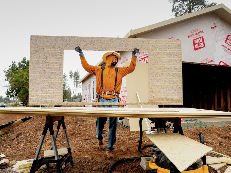 Jose Villanueva carries siding while building a home in Paradise on Oct. 25, 2023. The project is partly funded by ReCoverCA, a state program providing money to rebuild homes in disaster areas. Photo by Noah Berger, AP Photo