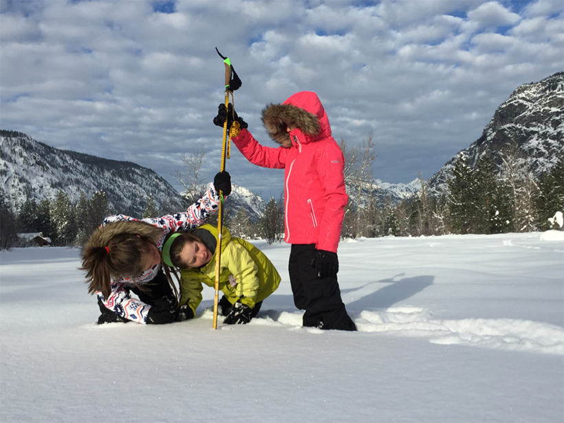 Young citizen scientists use a ski pole to collect snow depth data