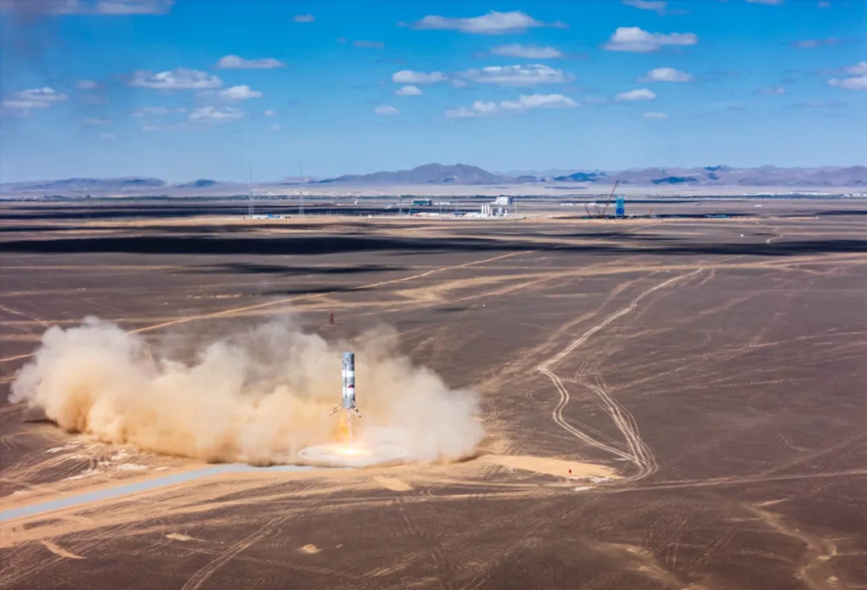 Sand and exhaust billow out from a desert landing pad as the Zhuque-3 rocket test article makes a powered descent.