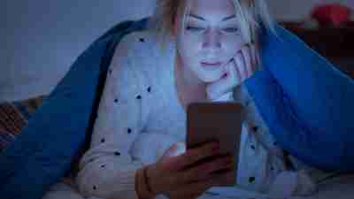 Anxious woman looking at her phone. Avoiding the news is one way to calm anxiety.