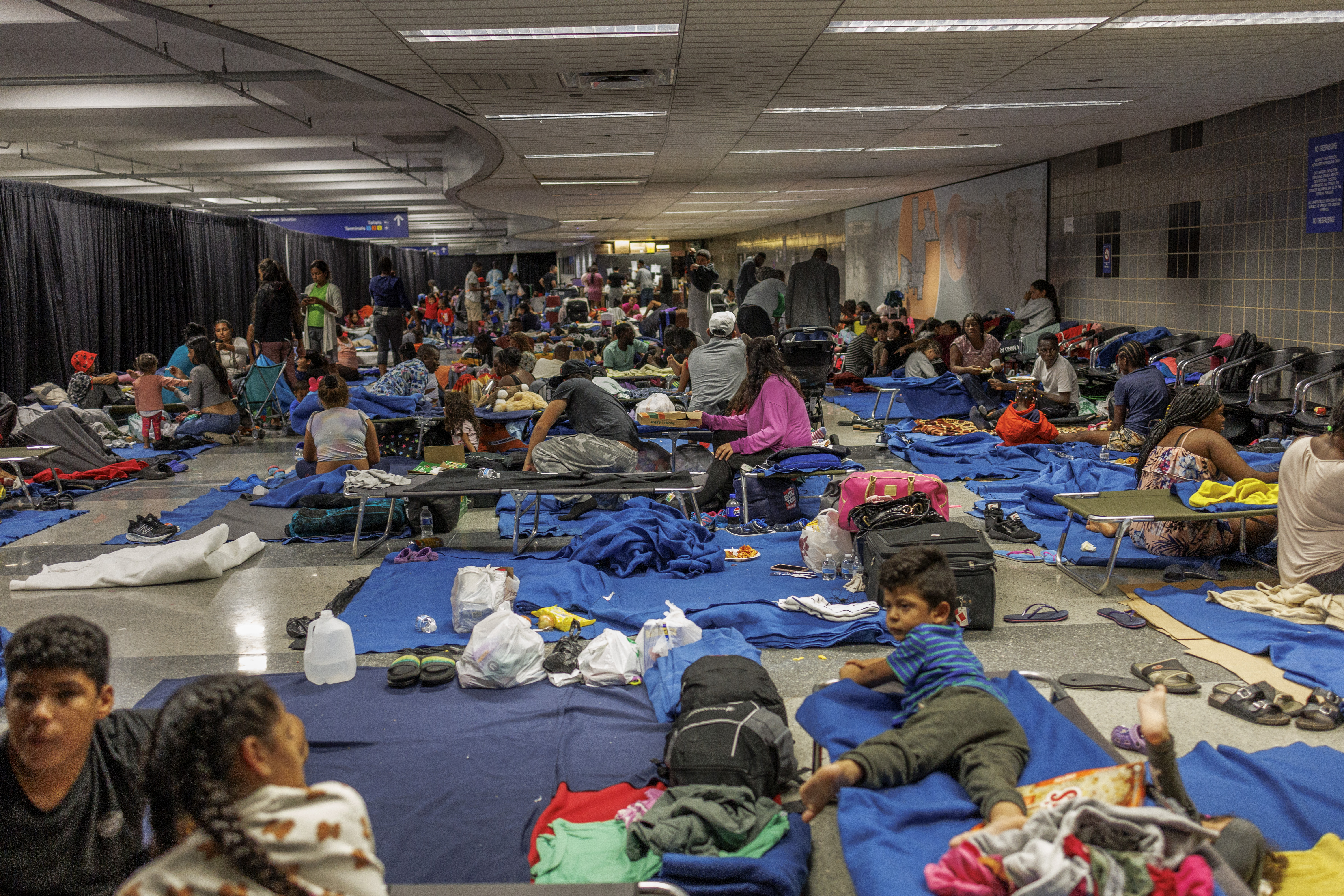 Recently arrived migrants sit on cots and the floor of a makeshift shelter operated by the city at O'Hare International Airport on Aug. 31, 2023. (Armando L. Sanchez/Chicago Tribune)