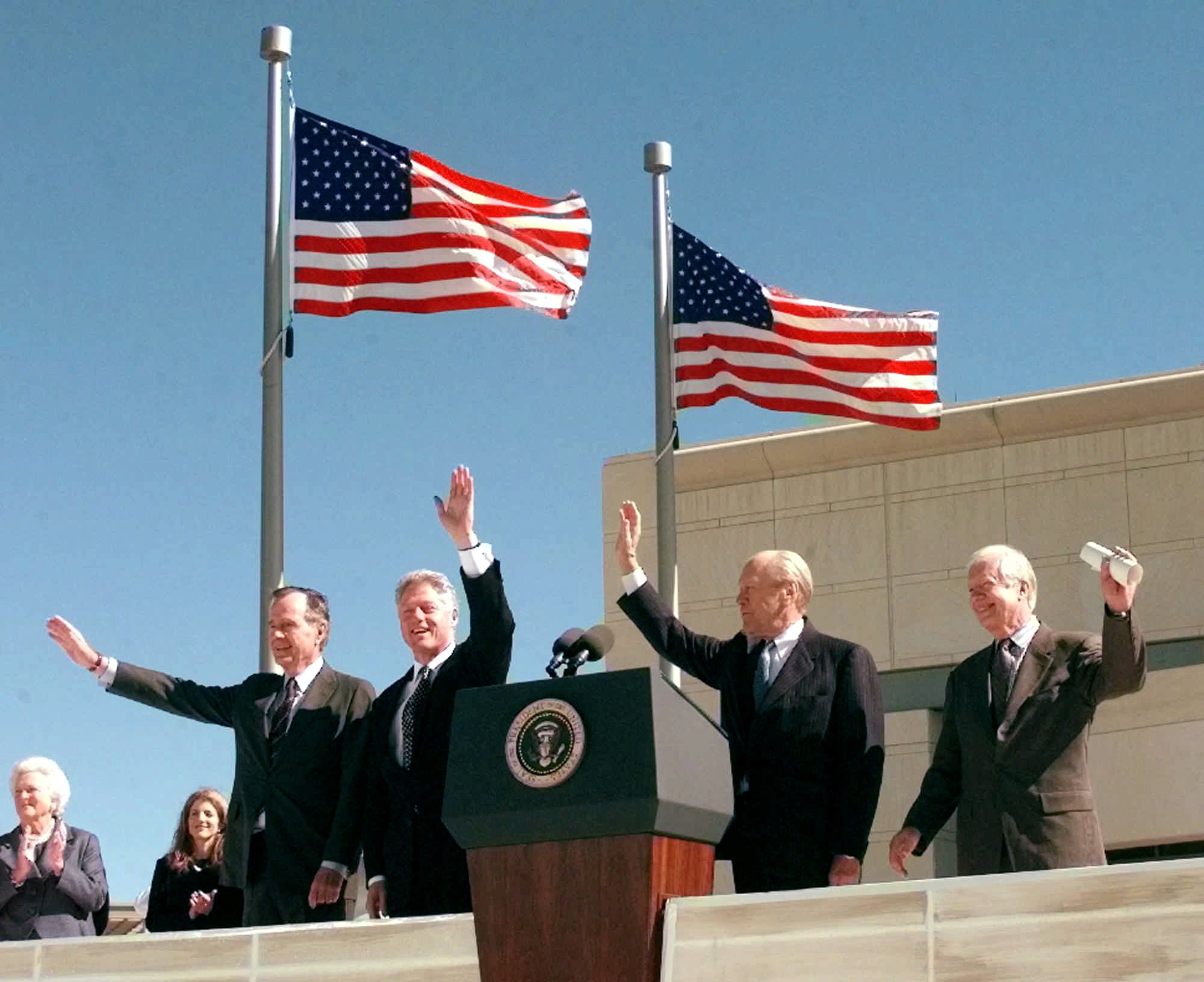 Former President George Bush, left, President Clinton, former President Gerald Ford, and former President Jimmy Carter, right, wave to the crowd at the dedication of the George Bush Presidential Library in College Station, Texas, Thursday, Nov. 6, 1997. (AP Photo/Susan Walsh)