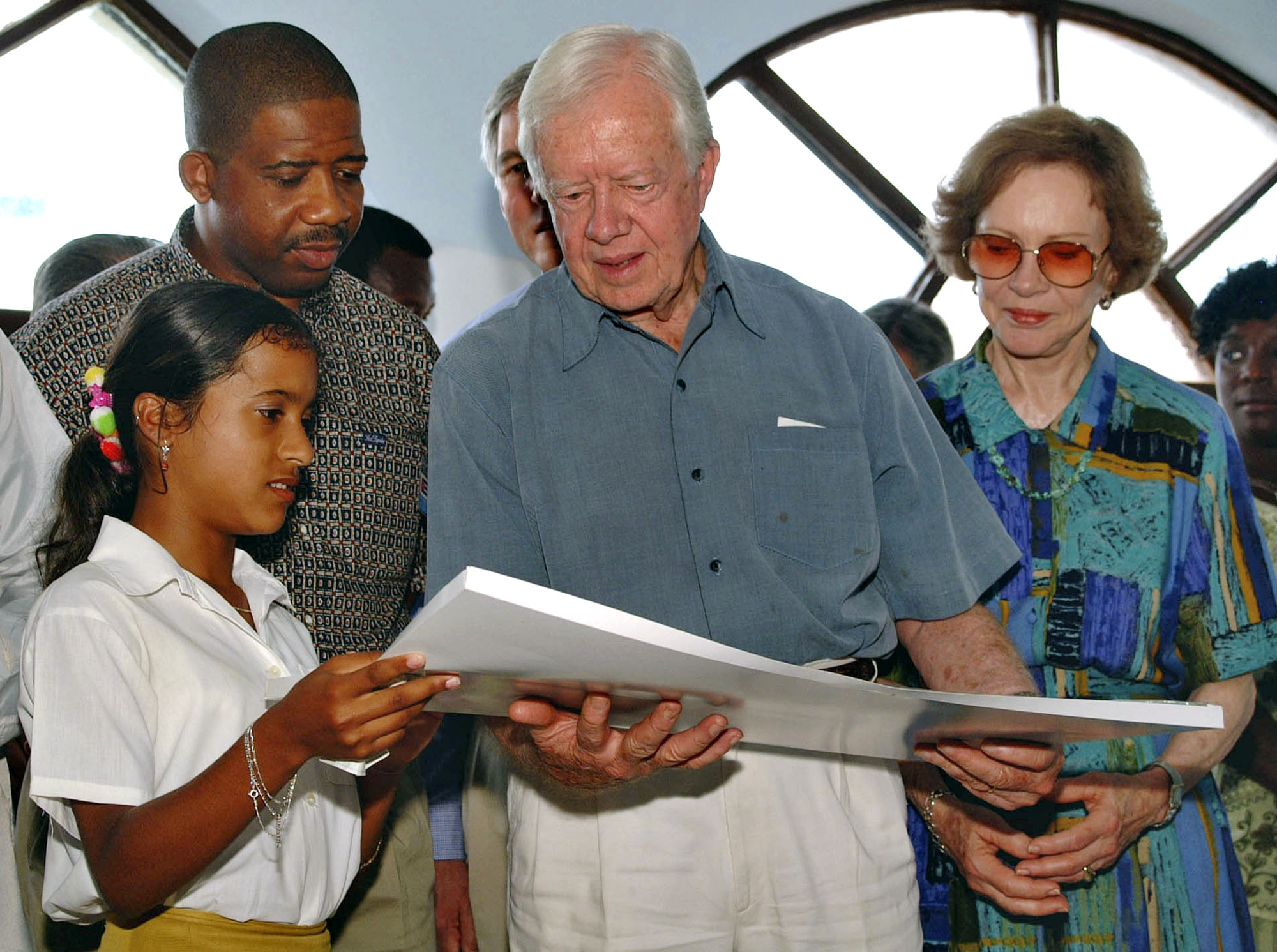 Former US President Jimmy Carter, center, and his wife Rosalynn, right, receive a drawing as a gift from Nudersi Garcia, 15, left, a patient at the "Los Cocos" AIDS sanatorium during his visit to the medical facility in Havana, Cuba Tuesday, May 14, 2001. (AP Photo/Cristobal Herrera)