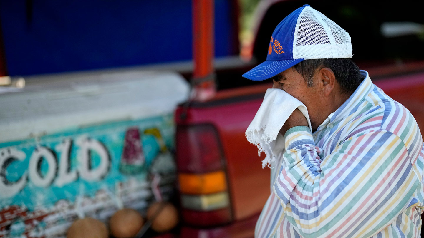 This image shows a man in Houston wiping sweat from his brow amid a record-breaking heat wave in June.