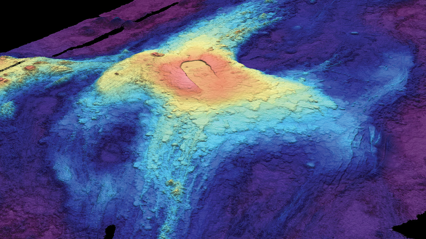 A heat map image of the ocean floor shows bloblike circles of red, yellow, and blues fading out from the volcano's center.