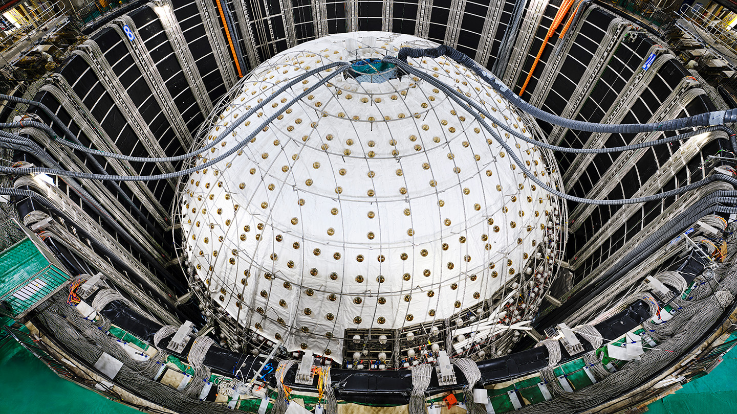 A sphere inside a large pit is covered in white sheeting with tubes entering a hole in the top.