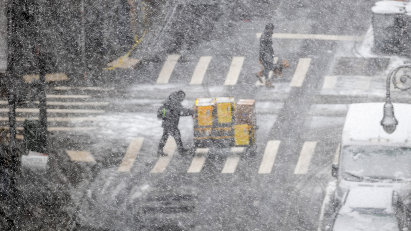 people cross a street during a major winter storm in New York City