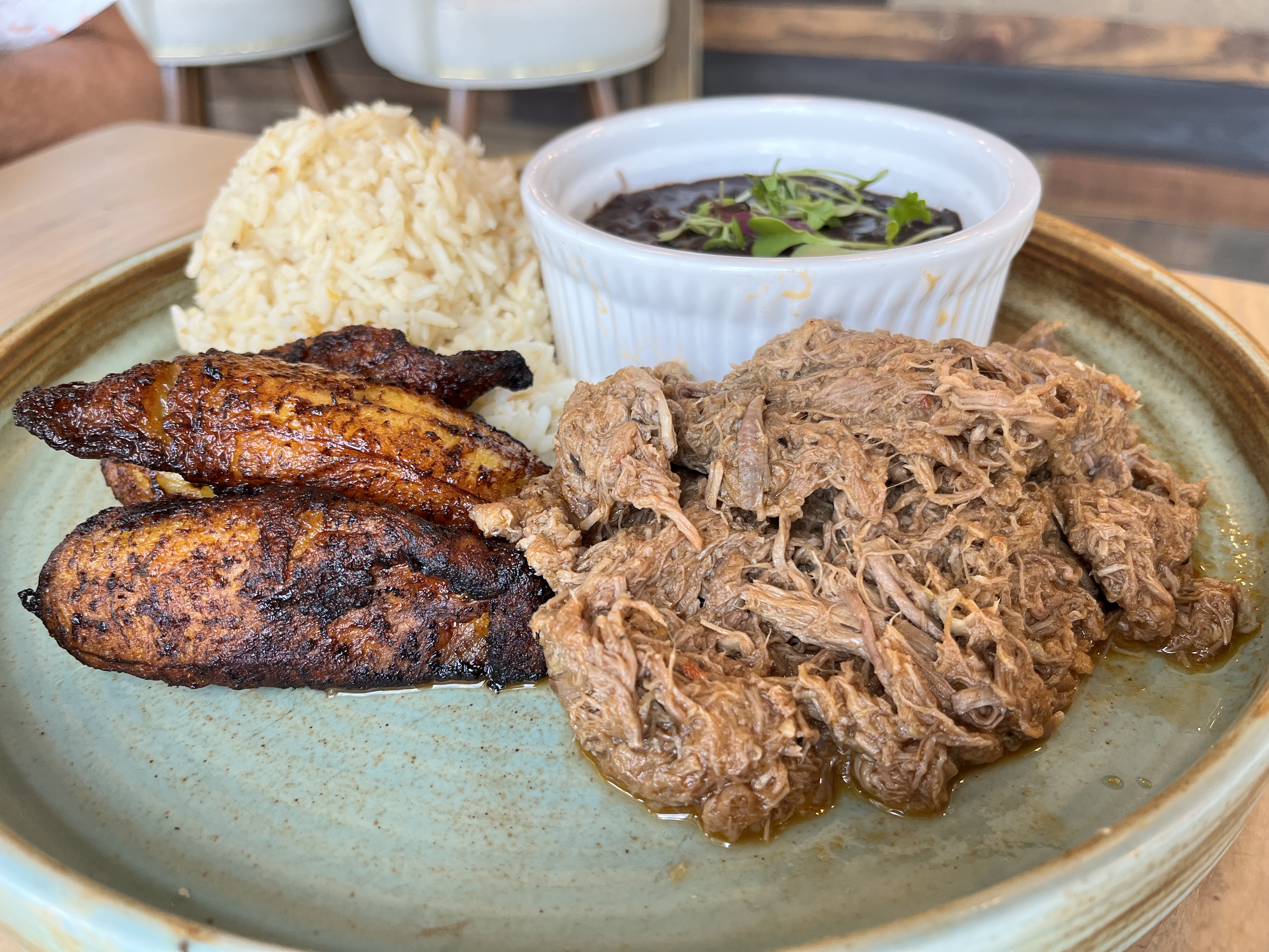 Shredded beef, plantains, black beans and rice on a plate