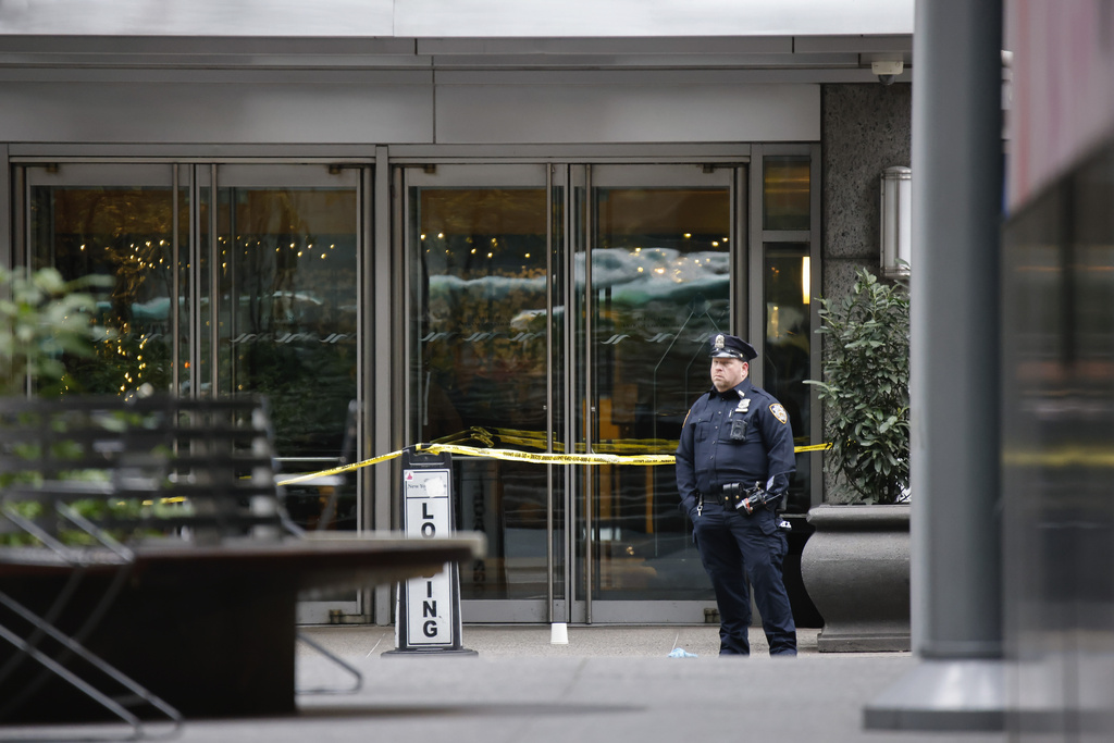 A police officer stands outside a building that is cordoned off with yellow tape.