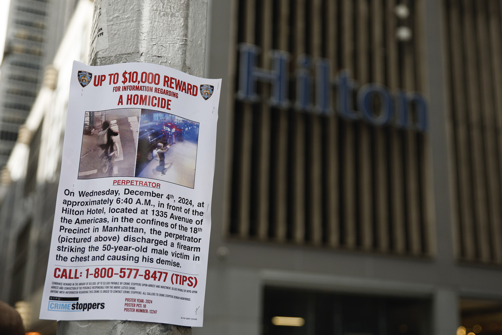 'Up to $10,000 reward,' says a small flier taped to a light pole, with a building marked with "Hilton' signage in the background.