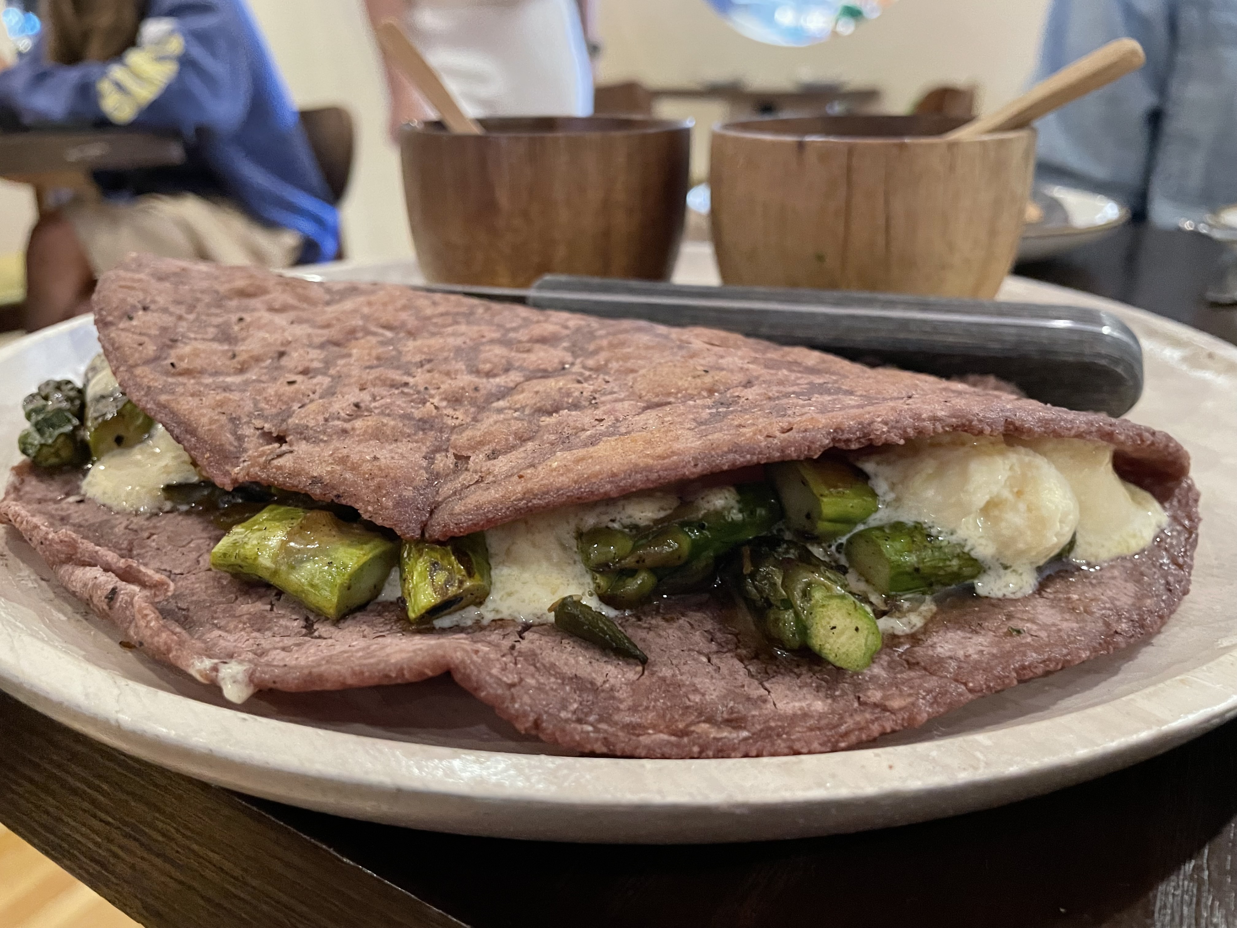 A blue corn tortilla stuffed with white cheese and green asparagus