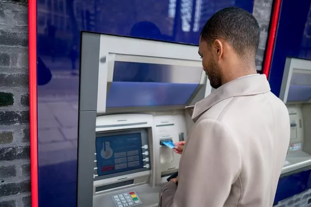 A man taking money from an ATM (cashpoint machine)