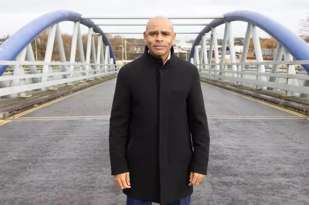 man wearing black jacket poses for photo on bridge