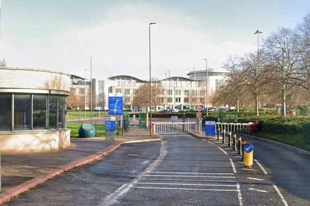 Office building with curvy roof behind main gates