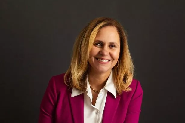 Woman with long blonde hair and red suit jacket posing for photo