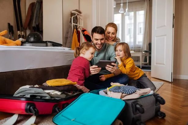 Happy family using tablet while packing for a winter vacation