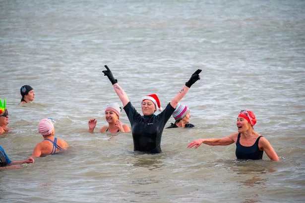 A woman with a Santa hat enjoys the cold water swim