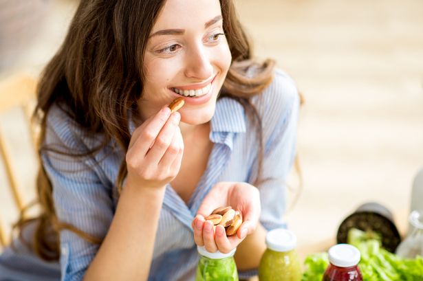 Closeup view from above of a woman eating brasil nuts with healthy food on the background