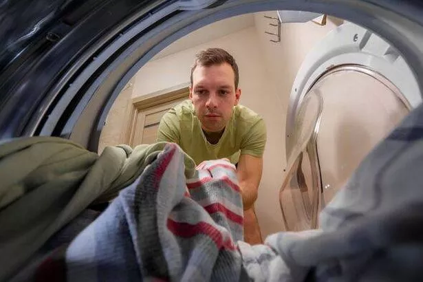 Man taking out clean washed clothes from washing machine