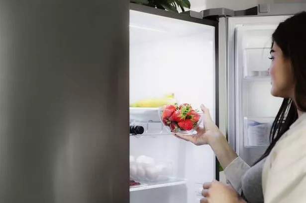 Woman taking strawberries from fridge