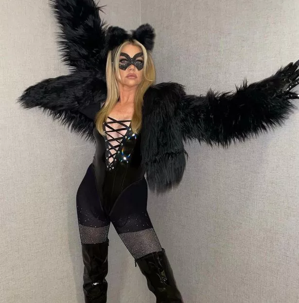 Denise wearing a fur coat and corset for Halloween