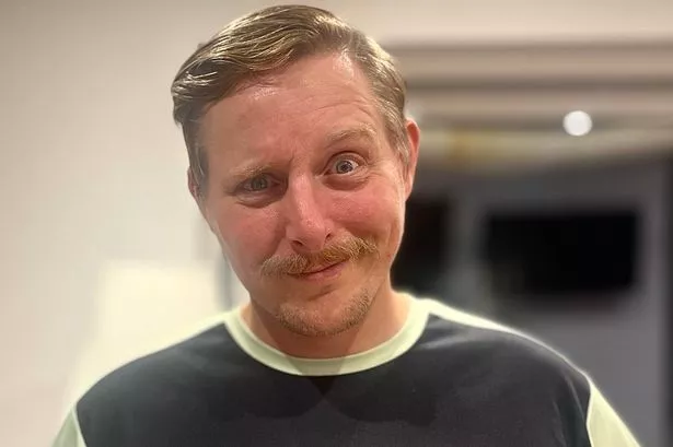 Man with a moustache wearing a T-shirt with a white moustache print for Movember