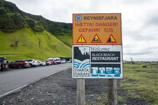 Sign reminding tourists and visitors of the dangers of sneaker waves at Reynisfjara Black Sand Beach.