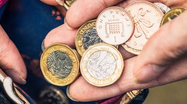 Close-up of a woman's hand holding one pound coins and other change from her purse.