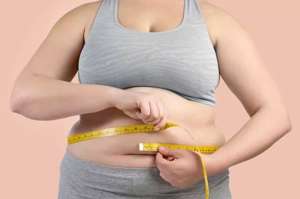 Overweight woman measuring her waist with a tape measure