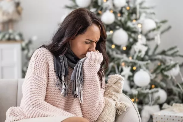 Woman in sweater feels ill as fever and flu ruin her Christmas festive period.