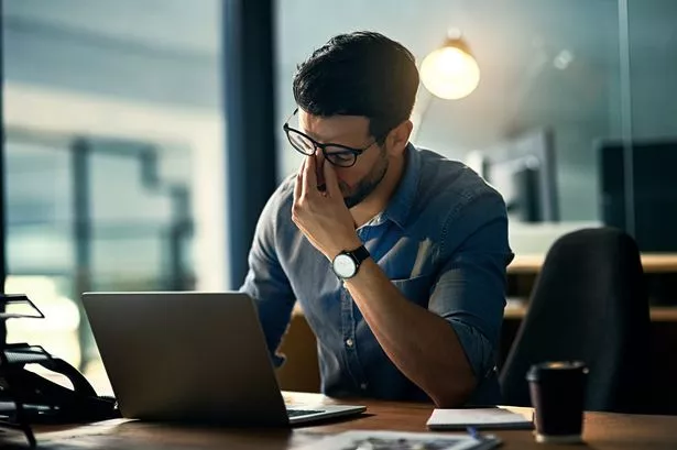 Shot of a young businessman experiencing stress during a late night at work