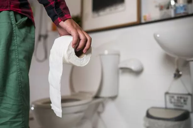 Midsection Of Man With Toilet Paper Standing In Bathroom