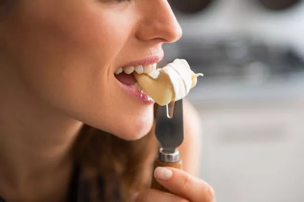 Person eating a slice of Camembert cheese