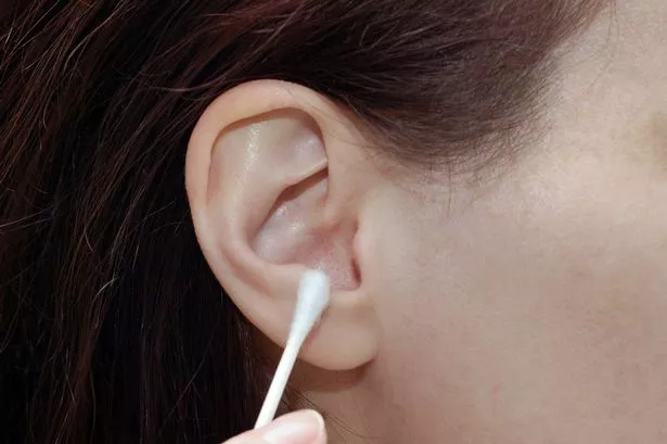 Close up of a woman about to use a cotton swab in her ear