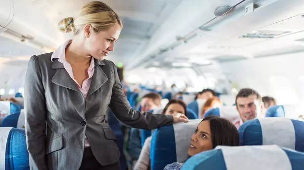 Smiling flight attendant talking to female passenger.