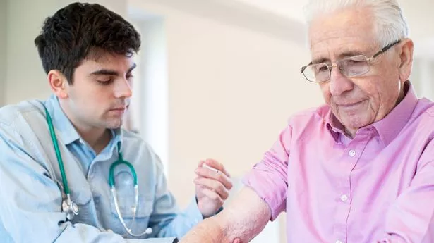 Male Doctor Giving Senior Man Vaccine Injection In Arm With Syringe