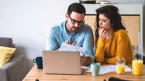 Concentrated young husband and wife hold paperwork busy paying household bills or taxes on laptop online, focused married couple manage finances, use internet banking service on computer