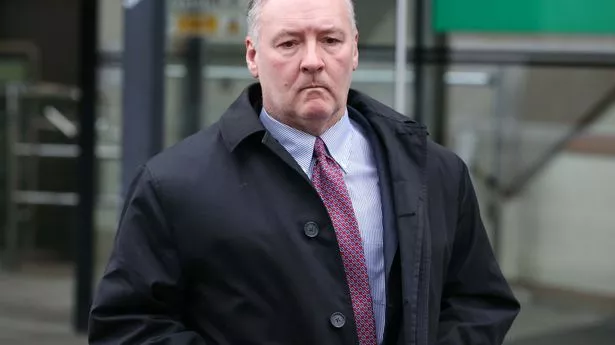 Bolding man with blue shirt, pink tie and unbuttoned black jacket