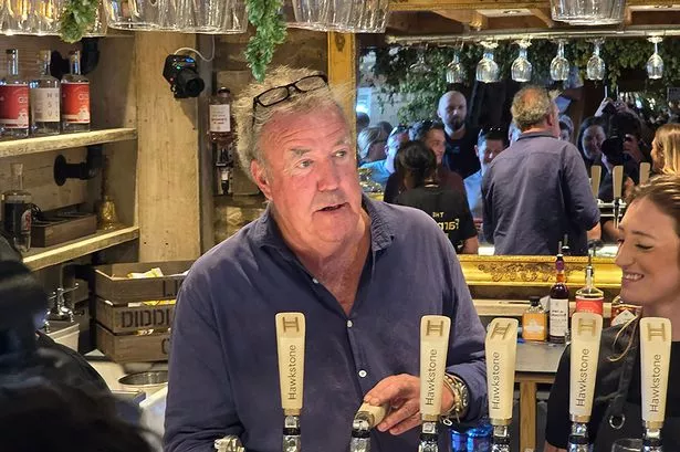 Jeremy Clarkson behind the bar at his pub as someone pours drinks