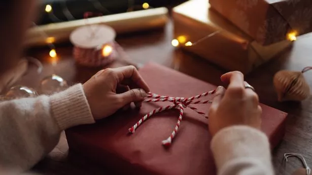 Close-up of female hand tying a bow on Christmas gift. Christmas sale.