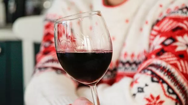 Person in a Christmas sweater drinks wine alone