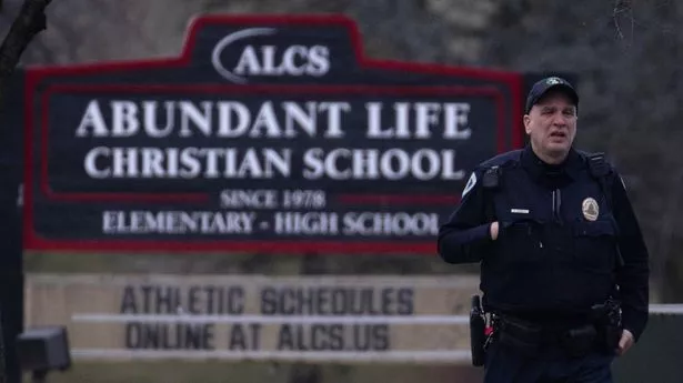 A police officer stands guard in front of Abundant Life Christian School