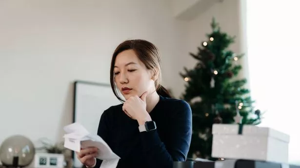 Young Asian woman looking stressed while going through various expense receipts and bills after Christmas shopping