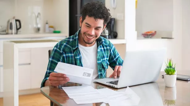 Happy Latin American man paying his utility bills online from home - home finances concepts