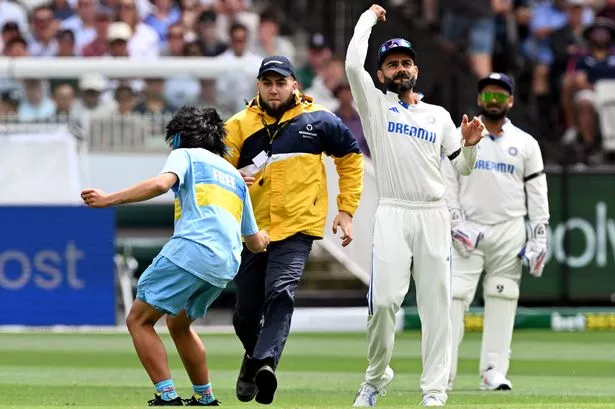 A pitch invader is tackled by security after approaching India's Virat Kohli